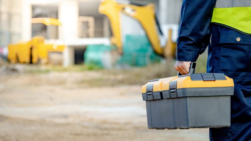 Male handyman hand carrying toolbox at construction site